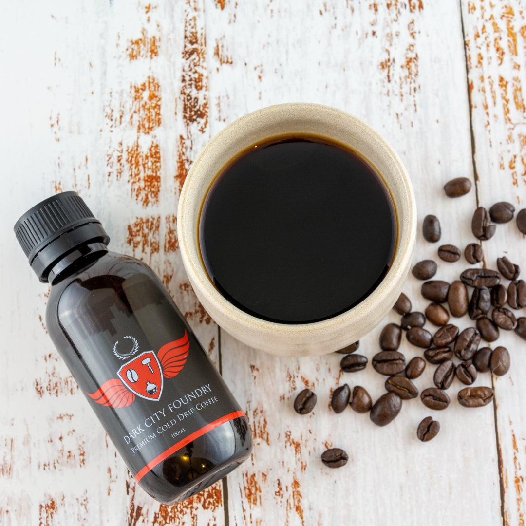 buy cold brew coffee Sydney. 100ml bottle picutred next to mug of coffee and scattered coffee beans. Flatlay image.